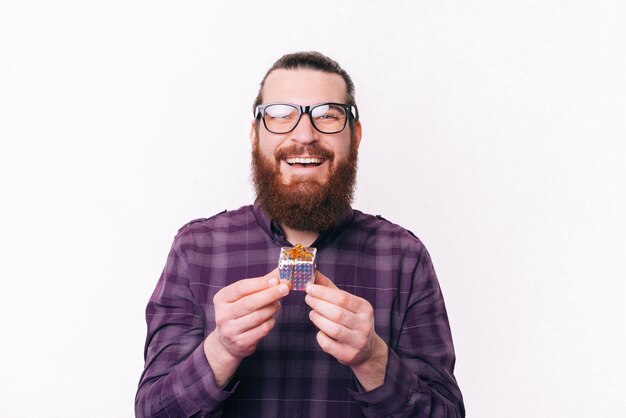 Retrato de jovem alegre com barba, usando óculos e segurando um pequeno presente