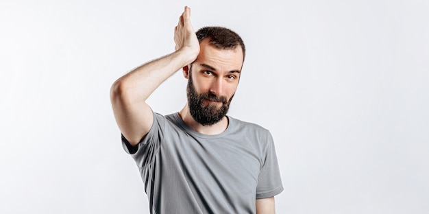 Retrato de jovem alegre, sorrindo enquanto olha para a câmera de mãos dadas para os lados em um fundo branco com espaço para simulação de publicidade