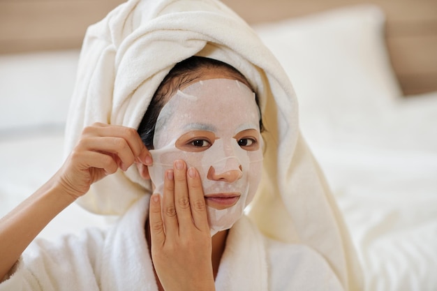 Retrato de jovem aplicando máscara facial enriquecida com soro iluminador