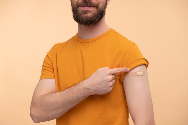 Retrato de jovem apontando para seu adesivo de vacina