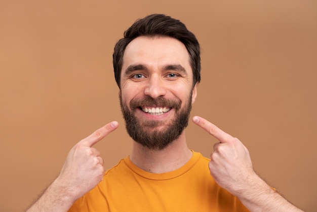 Foto retrato de jovem apontando para seu sorriso