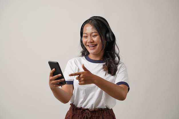 Retrato de jovem asiática usando telefone celular com expressão alegre, mostre algo no telefone