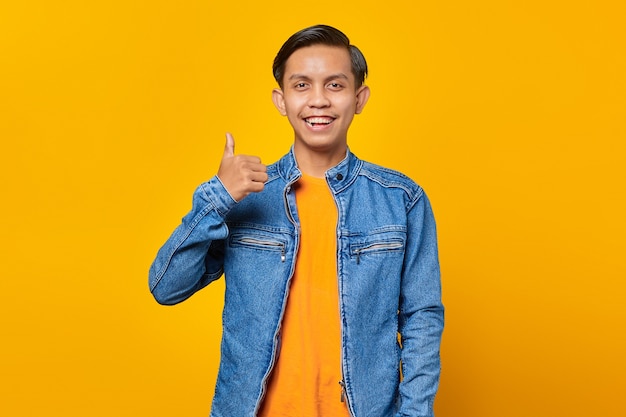 Retrato de jovem asiático alegre mostrando os polegares para cima ou sinal de aprovação