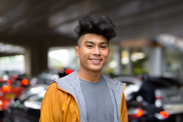 Retrato de jovem asiático com cabelos cacheados na cidade