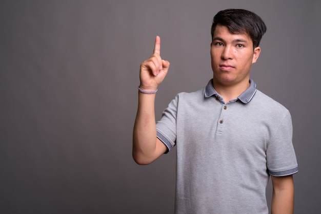 Retrato de jovem asiático contra uma parede cinza