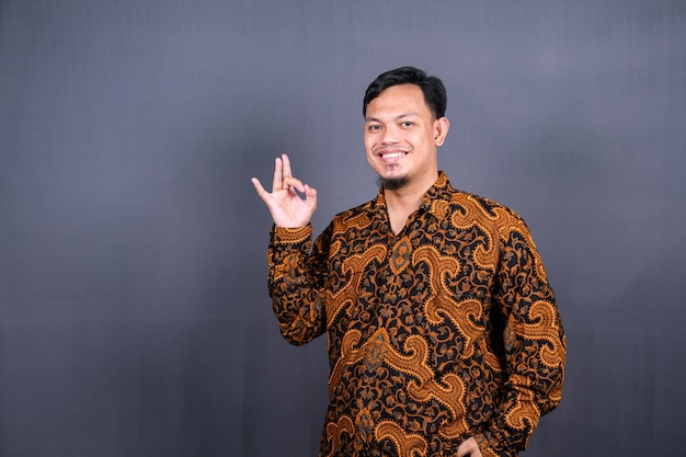 retrato de jovem asiático em um batik posando isolado em fundo cinza