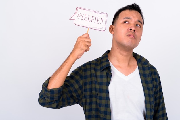 Retrato de jovem asiático pensando com uma placa de papel de selfie