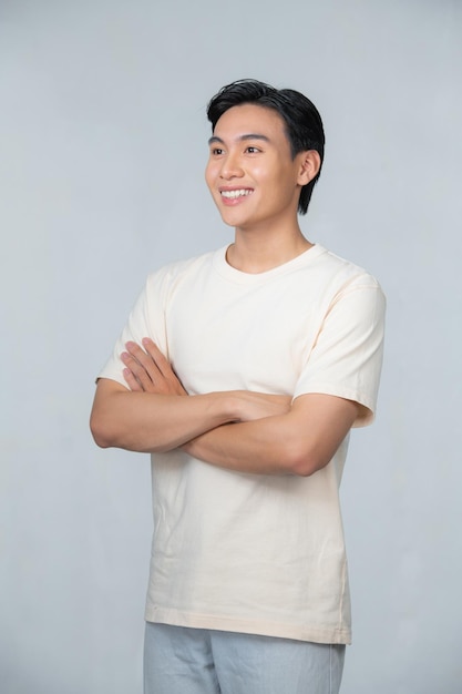 Retrato de jovem asiático sorridente com os braços cruzados isolados no branco