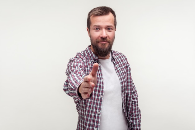 Retrato de jovem barbudo amigável em camisa xadrez casual em pé dando a mão ao aperto de mão, conhecendo-se na entrevista de emprego, conhecendo novas pessoas. tiro de estúdio interior isolado no fundo branco