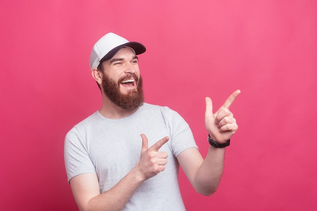 Retrato de jovem barbudo apontando para fora a sorrir