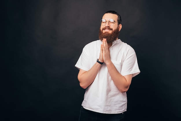 Retrato de jovem barbudo orando por algo e desejando