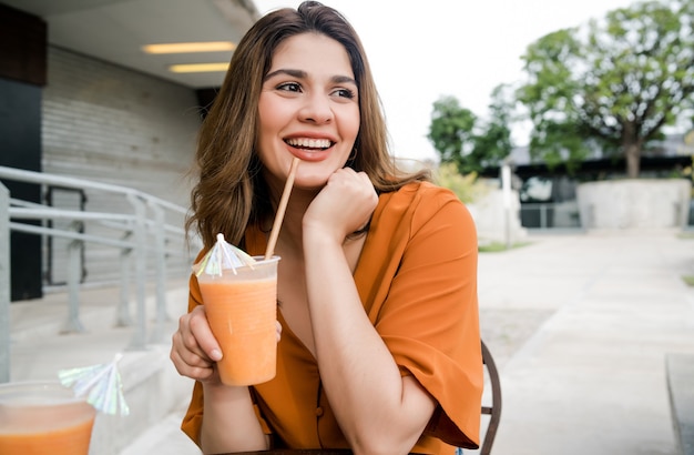 Retrato de jovem bebendo uma fruta de suco fresco em um café ao ar livre Conceito urbano.