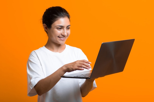 Retrato de jovem blogueira indiana adulta sorridente trabalhando com um computador laptop