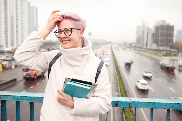 Retrato de jovem blogueiro feliz com laptop moderno e cadernos ao ar livre