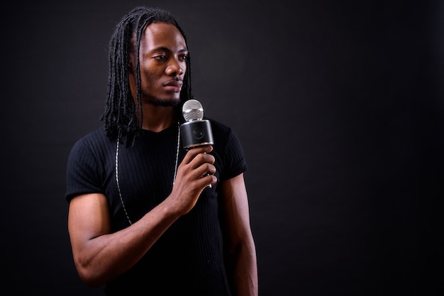 Retrato de jovem bonito africano com dreadlocks no preto