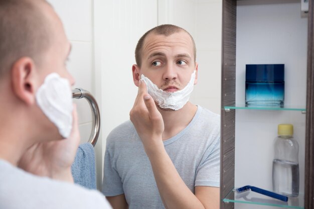 Retrato de jovem bonito aplicando espuma de barbear no rosto