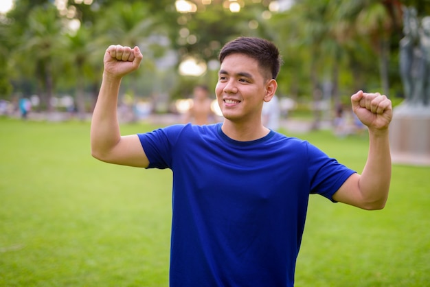 Retrato de jovem bonito asiático relaxando no parque em Bangkok, Tailândia