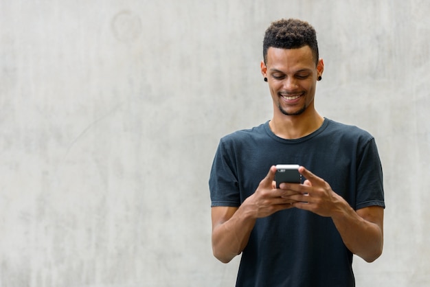 Retrato de jovem bonito barbudo africano contra uma parede de concreto ao ar livre