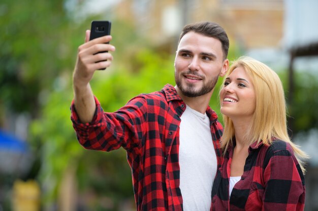 Retrato de jovem bonito barbudo e jovem loira linda juntos na rua ao ar livre