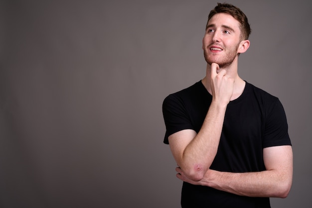 Retrato de jovem bonito contra cinza