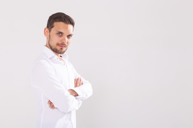 Retrato de jovem bonito e feliz em uma camisa casual em pé contra um fundo branco com espaço de cópia