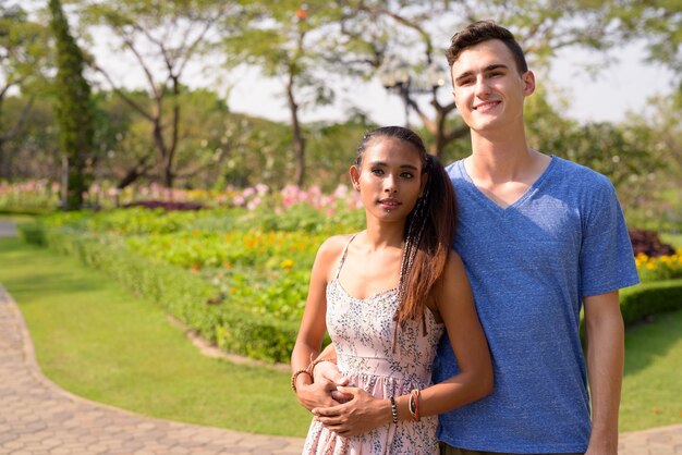 Retrato de jovem bonito e jovem mulher asiática relaxando juntos no parque