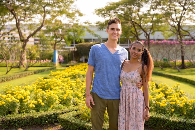 Retrato de jovem bonito e jovem mulher asiática relaxando juntos no parque