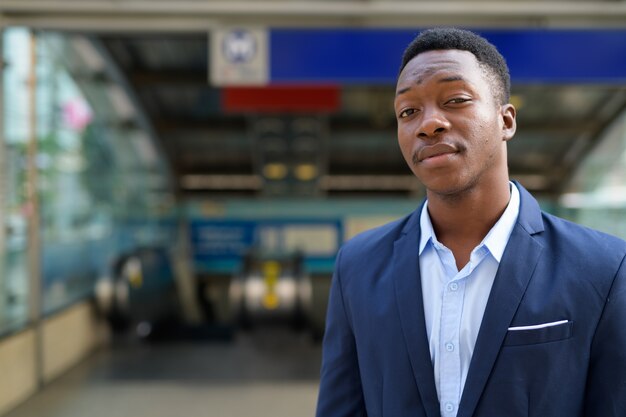 Retrato de jovem bonito empresário africano do lado de fora da estação de trem do metrô