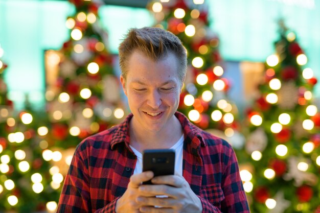 Retrato de jovem bonito hippie em árvores de Natal iluminadas ao ar livre