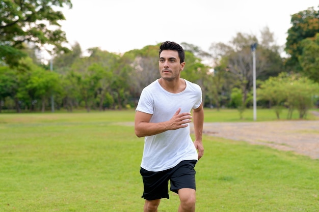 Retrato de jovem bonito hispânico no parque ao ar livre