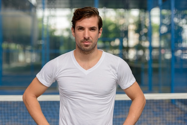 Retrato de jovem bonito hispânico pronto para jogar na quadra de padel