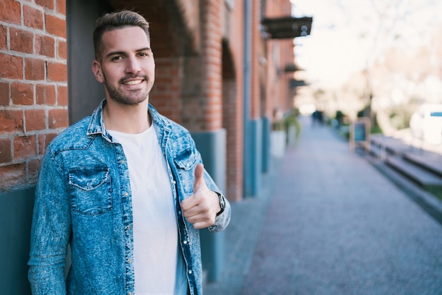 Retrato de jovem bonito vestindo roupas casuais ao ar livre na rua