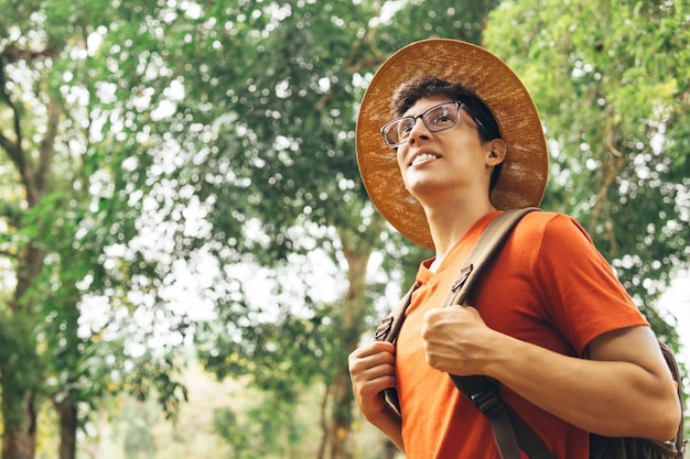 Retrato de jovem caminhante hispânico usando um telefone celular curtindo a natureza na floresta