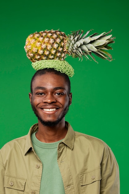 Foto retrato de jovem carregando abacaxi na cabeça