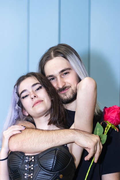 Retrato de jovem casal abraçando e sorrindo para a câmera Casal apaixonado segurando uma rosa abraçando e olhando para a câmera