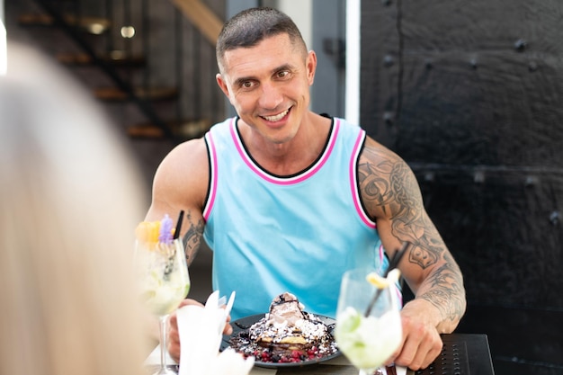 Retrato de jovem casal comendo panquecas ao ar livre restaurante e bebendo coquetel