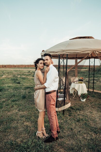 Retrato de jovem casal namorando em uma barraca transparente com mesa servida