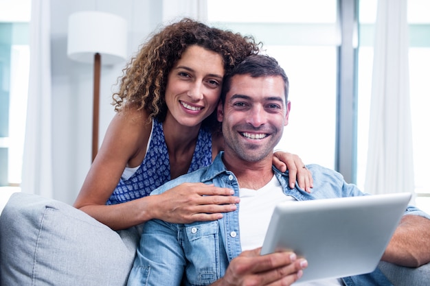 Retrato de jovem casal usando um tablet digital no sofá