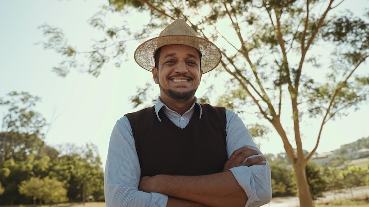Foto retrato de jovem com as mãos cruzadas na camisa casual na fazenda no fundo do céu colorido