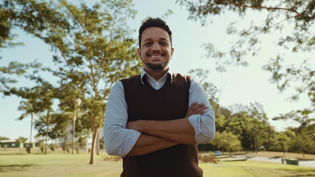 Retrato de jovem com as mãos cruzadas na camisa casual na fazenda no fundo do céu colorido