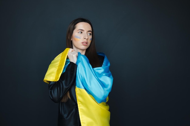 Retrato de jovem com bandeira ucraniana azul e amarela na bochecha em fundo preto