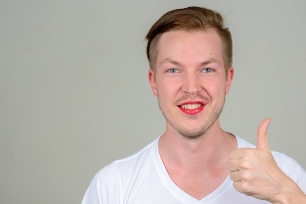 Retrato de jovem com barba por fazer usando maquiagem