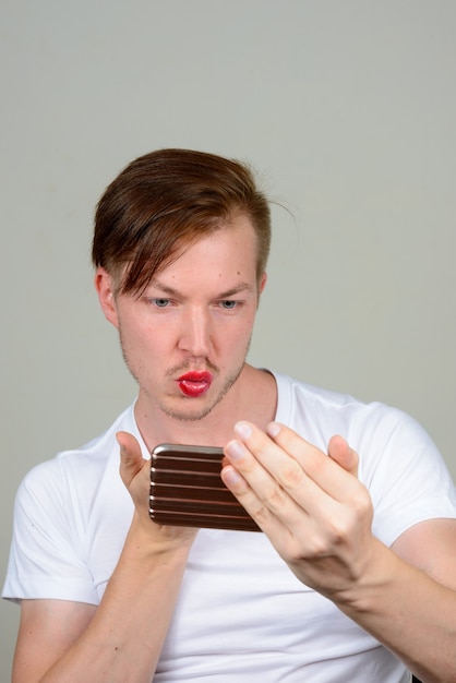 Retrato de jovem com barba por fazer usando maquiagem