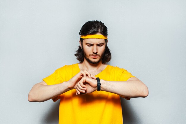 Retrato de jovem com cabelo comprido, vestindo uma camisa amarela usando smartwatch.