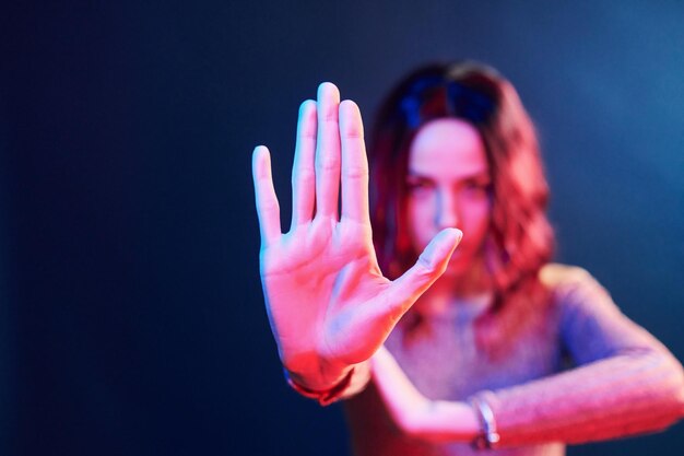 Foto retrato de jovem com cabelo encaracolado em neon vermelho e azul em estúdio