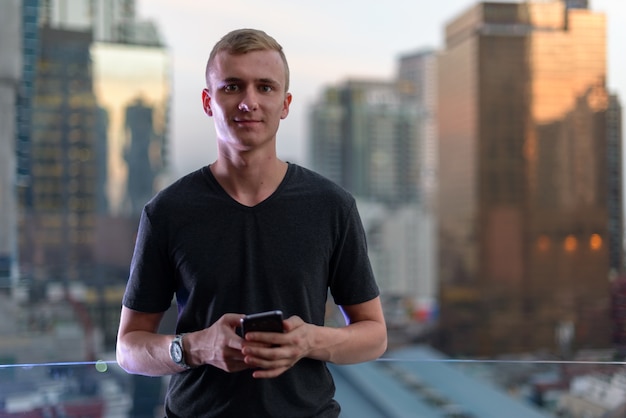 Retrato de jovem com cabelo loiro contra a vista da cidade ao ar livre