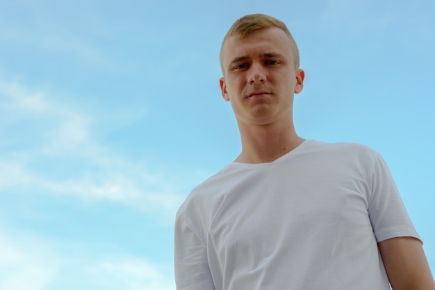 Retrato de jovem com cabelo loiro contra a vista do céu claro ao ar livre