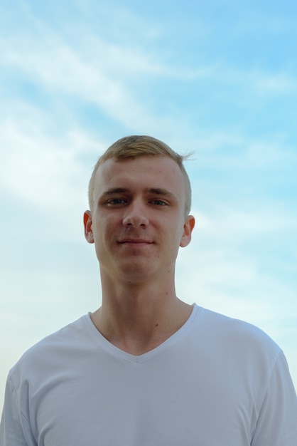 Retrato de jovem com cabelo loiro contra a vista do céu claro ao ar livre