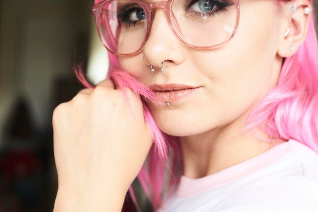 Retrato de jovem com cabelo rosa, óculos e piercings
