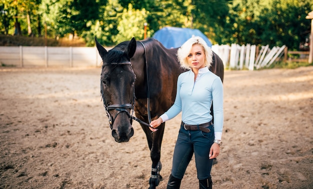 Retrato de jovem com cavalo castanho. Esporte equestre, senhora atraente e belo garanhão